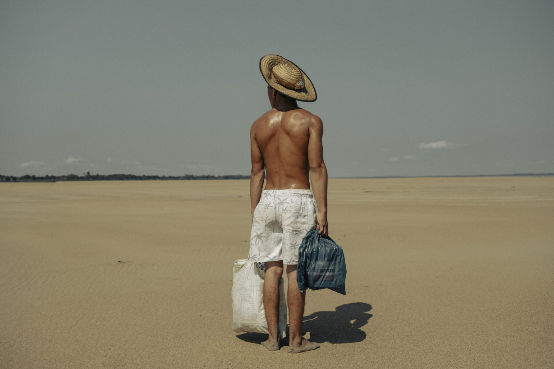 A young man named Cordeiro Freitas helps his mother carry food from the point where boats dock to the fishing community of Maracapuru, walking nearly 2 kilometers under the intense sun.-Droughts in the Amazon, especially in the Amazon, Negro, and Solimões rivers, are reaching alarming levels. One of the major tributaries of the Amazon River has recorded its lowest level in history, as reported by Brazil's geological service, reflecting a severe drought that has devastated the Amazon rainforest and other parts of the country.At the beginning of October, the level of the Negro River at the port of Manaus was 12.66 meters, compared to its normal level of around 21 meters. This is the lowest level recorded since measurements began 122 years ago. Water levels in the Amazon naturally fluctuate between the rainy and dry seasons, but this year's dry season has been much more severe than usual. All major rivers in the Amazon basin are at critical levels, including the Madeira River, the longest tributary of the Amazon.This phenomenon, associated with climate change, threatens not only biodiversity and river ecosystems but also the livelihoods of local communities that depend on these rivers for sustenance. Many of these communities have been cut off, and their boats have become stranded on large sandbanks. Due to the projected recurrence of droughts in the coming years, several communities are considering abandoning their territories and migrating to cities.